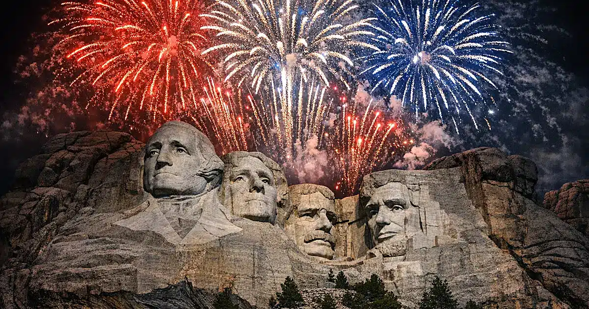 Fireworks bursting above Mount Rushmore's presidential sculptures at night in red, white, and blue colors