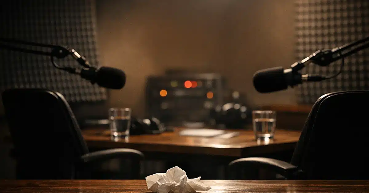Empty podcast studio with two chairs and microphones, tissue on table suggesting emotional interview
