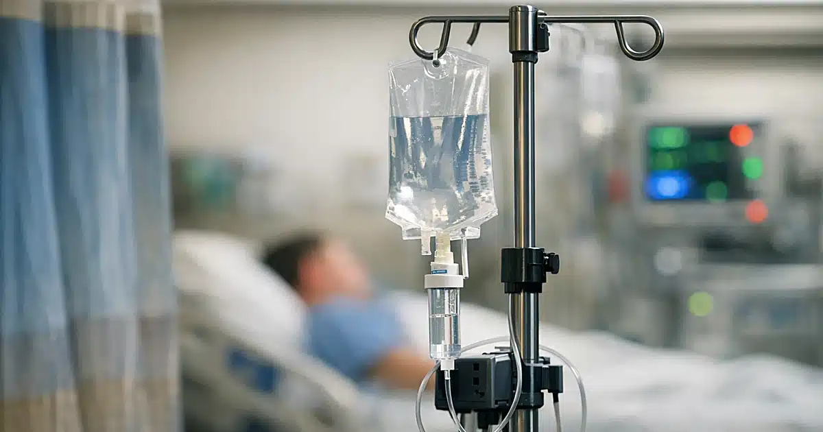 Hospital IV stand with medical equipment in a patient room with monitoring devices in background