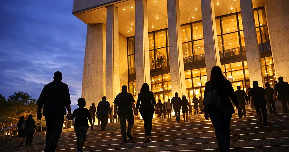 Silhouetted crowds ascending illuminated steps of modern presidential center at dusk