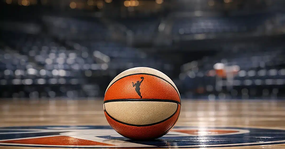 Basketball on empty professional arena court under stadium lights with blurred seating in background