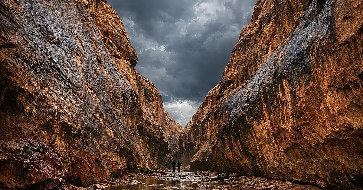 Narrow red rock canyon with dark storm clouds overhead showing flash flood terrain in Utah wilderness