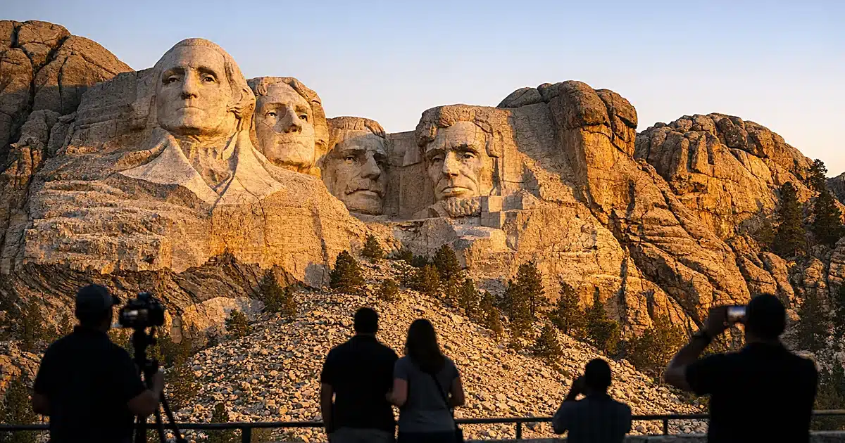 Mount Rushmore monument with four presidential faces carved in granite cliff at golden hour
