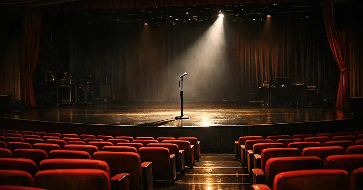 Empty theater seats facing an illuminated stage with lone microphone stand in a Las Vegas showroom