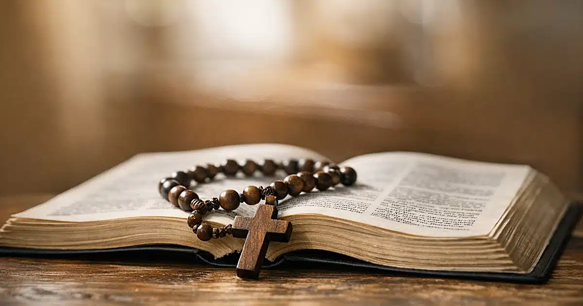 Rosary beads resting on open Bible on wooden table in natural window light