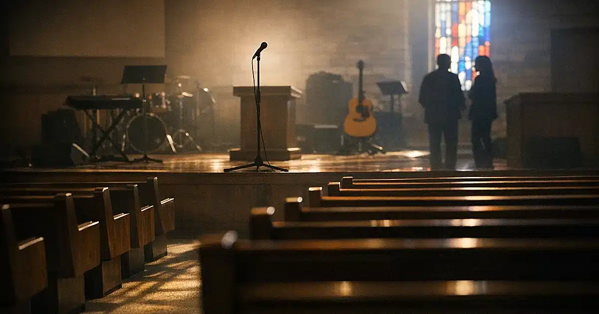 Empty church sanctuary with microphone stand and pews in dramatic window lighting