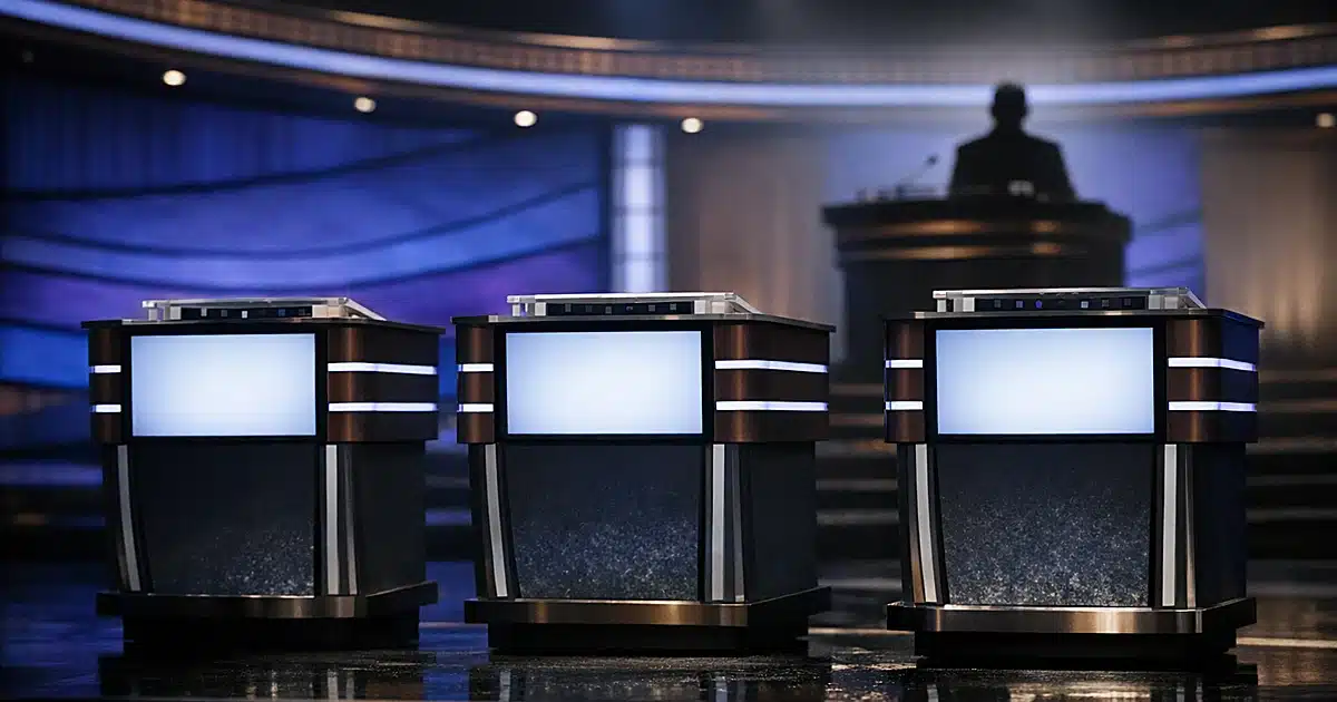 Empty game show contestant podiums with blank screens in television studio lighting
