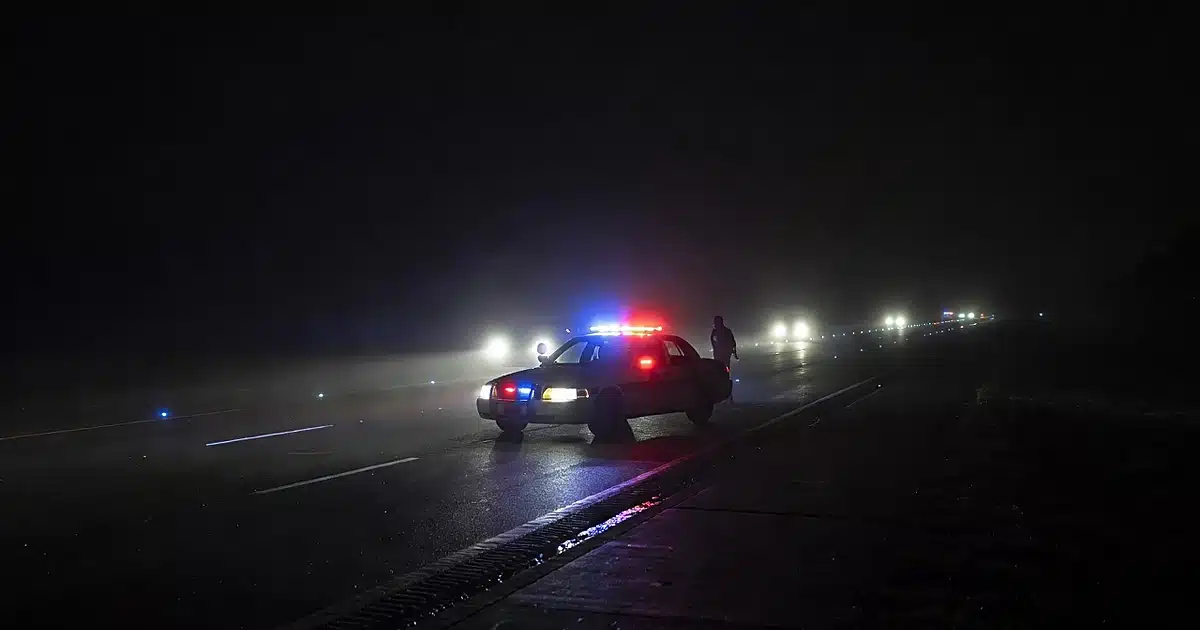 State police patrol car with emergency lights on dark foggy interstate highway at night