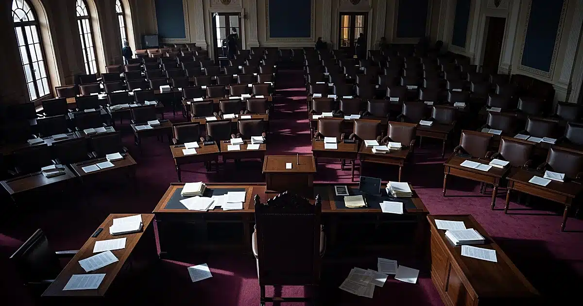 Empty legislative chamber with scattered papers on desks and dramatic window lighting creating shadows