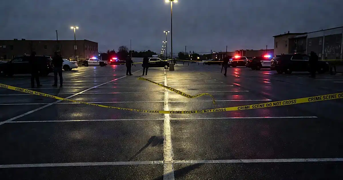 Empty parking lot at dusk with crime scene tape and police vehicle lights reflecting on wet pavement