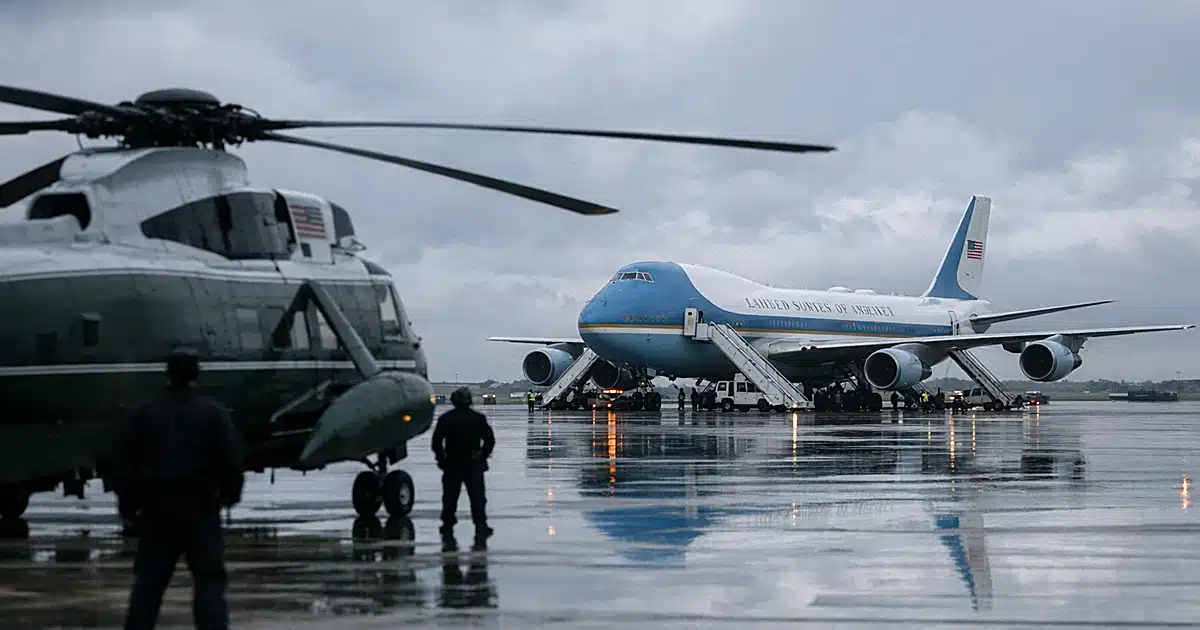Air Force One Boeing 747 on tarmac with boarding stairs deployed and ground crew silhouettes working near aircraft