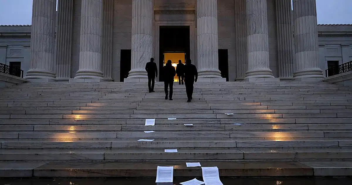 Silhouetted figures ascending wet courthouse steps at dusk with scattered documents and columned entrance