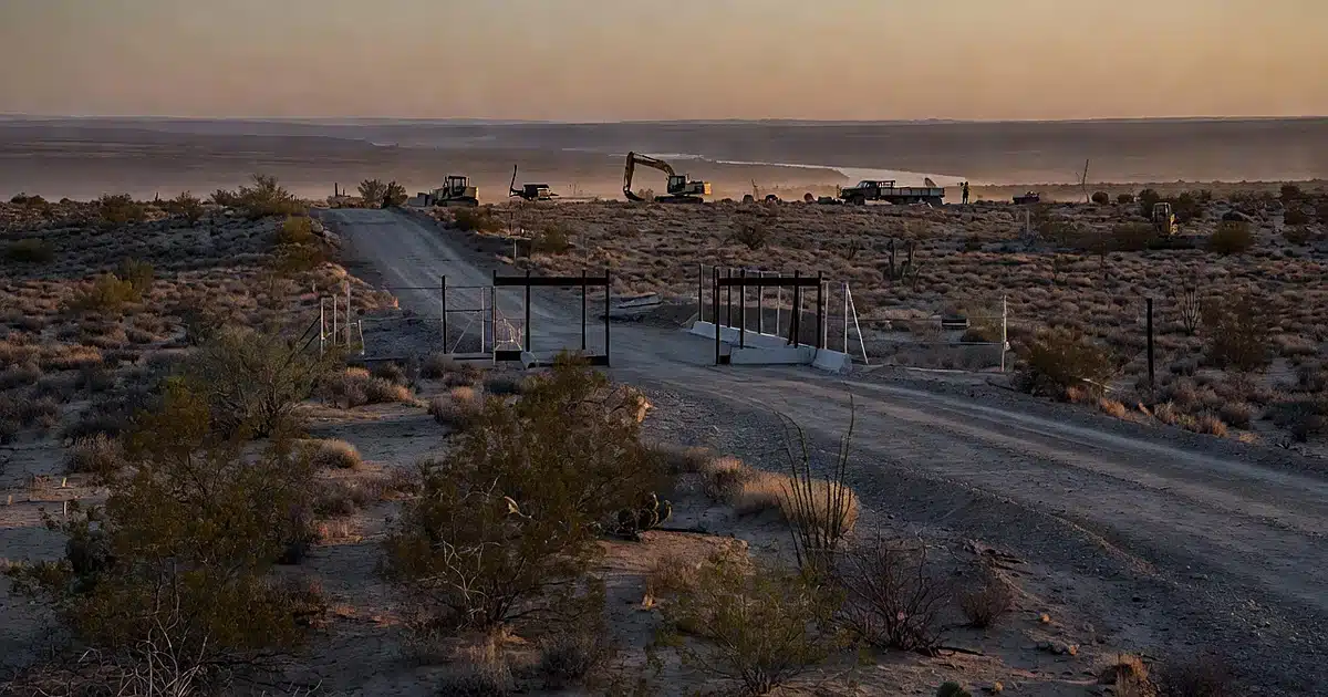 Idle construction equipment and partial vehicle barrier in Big Bend desert landscape at dusk