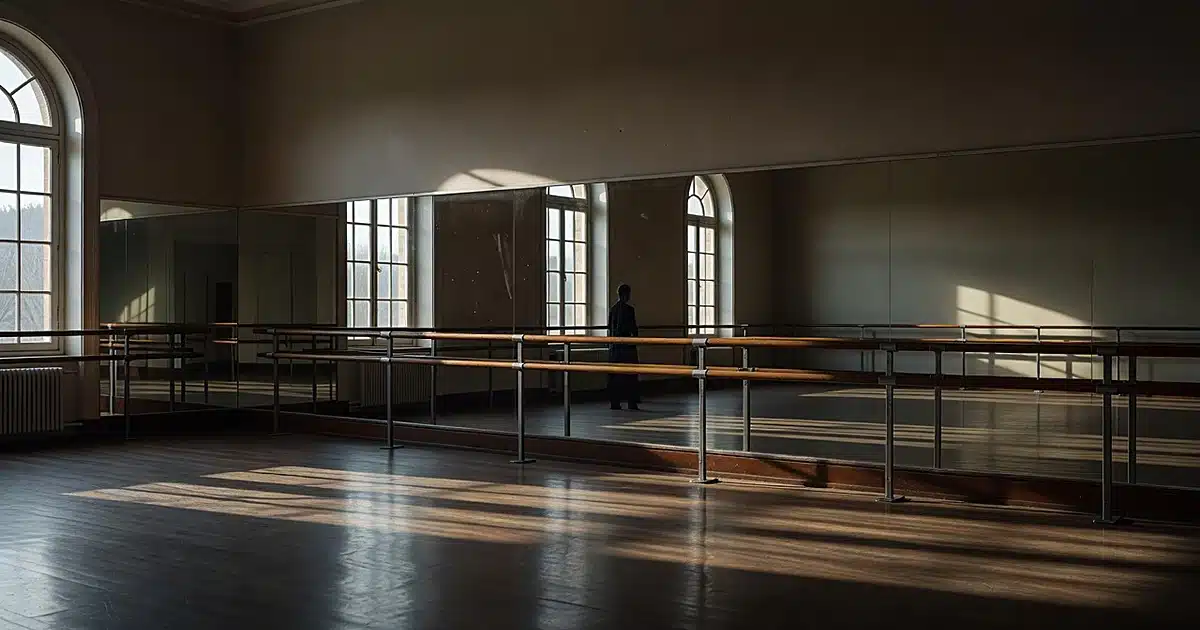 Empty ballet studio with wooden barre and mirrors in dramatic afternoon light