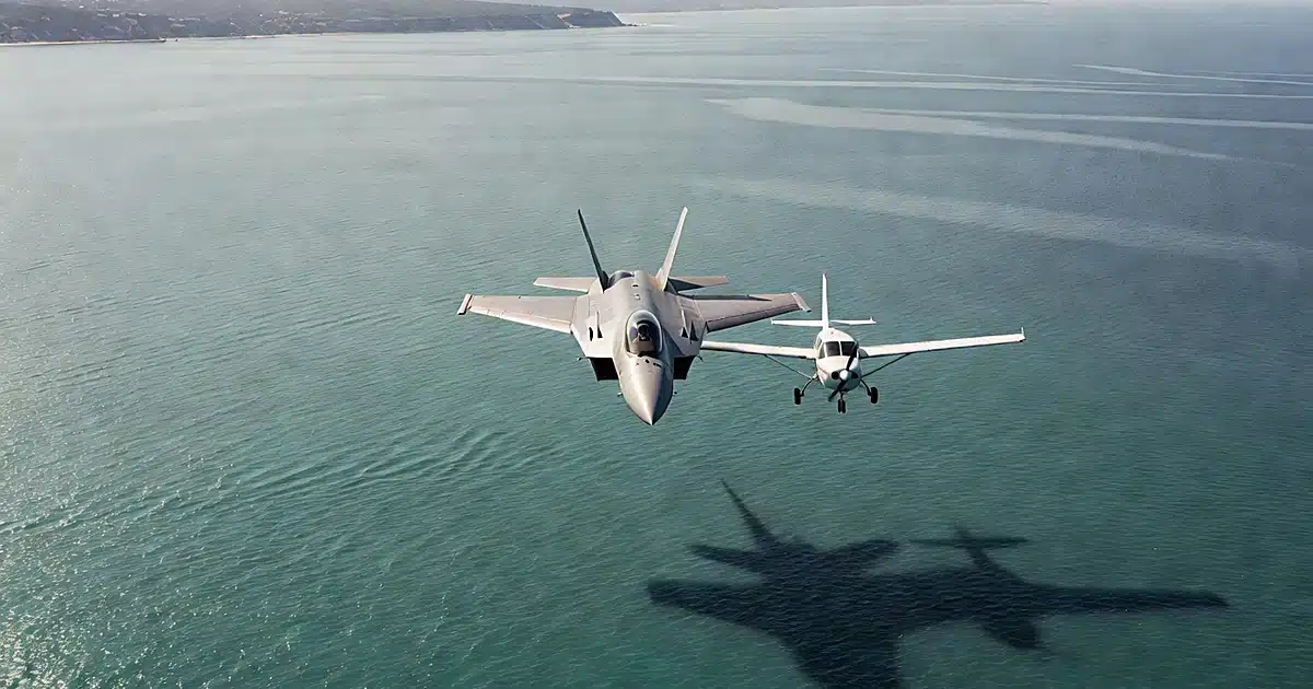 Military fighter jet intercepting small civilian aircraft over coastal waters in close proximity maneuver