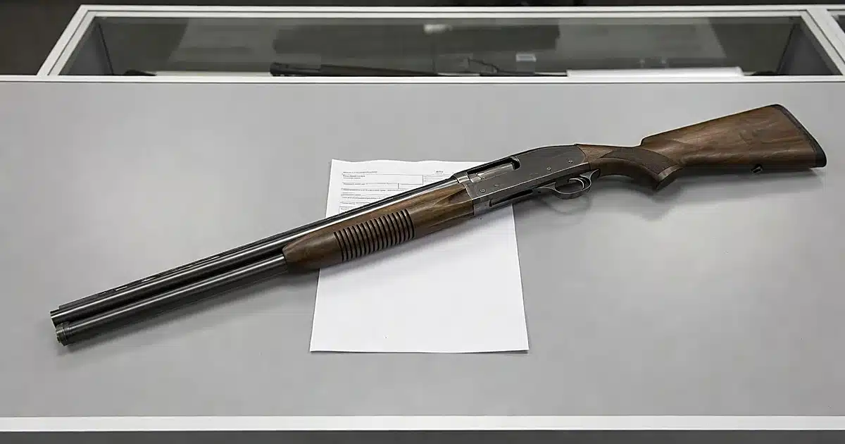 Shotgun on blank purchase paperwork at gun store counter under fluorescent lighting