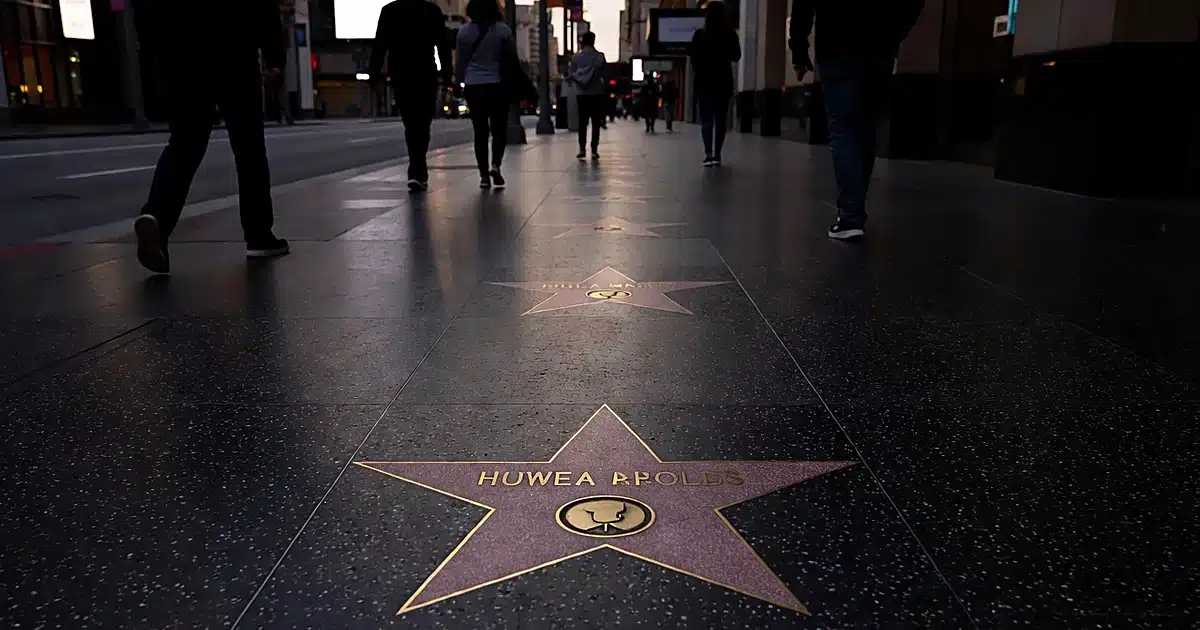 Hollywood Walk of Fame star embedded in terrazzo pavement with pedestrian silhouettes passing by at dusk