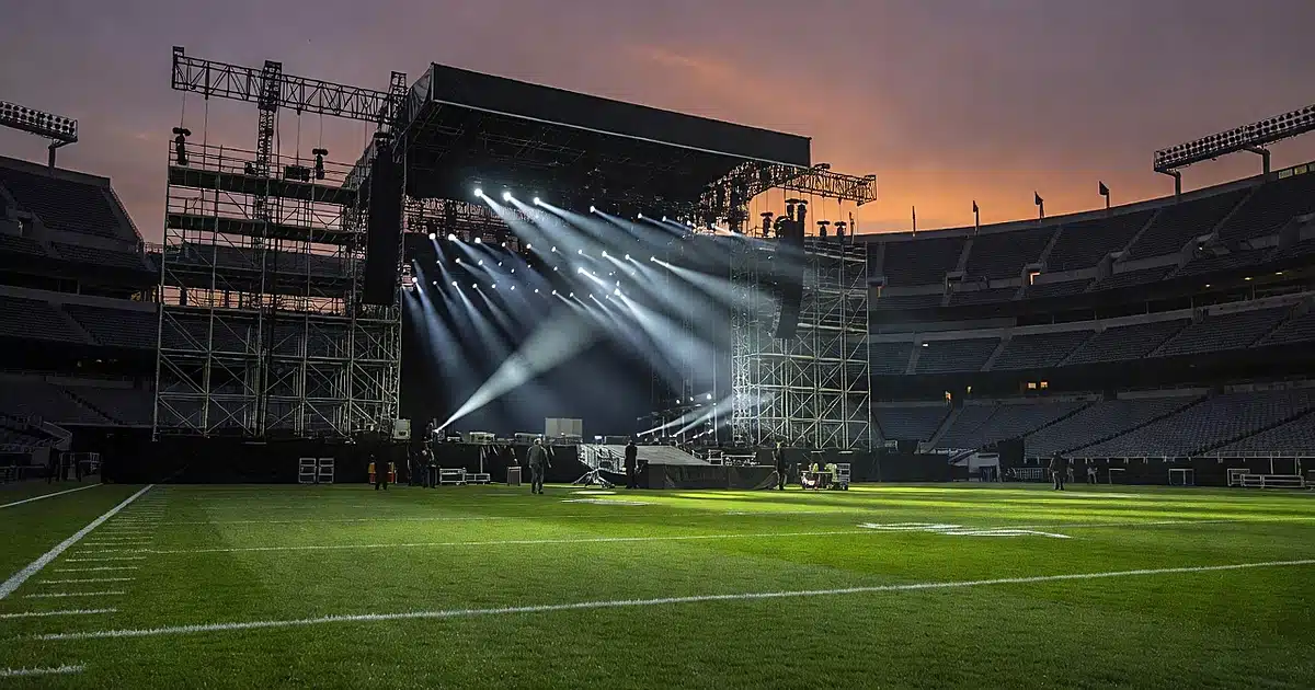 Empty football stadium at dusk with large halftime show stage structure at center field under dramatic lighting