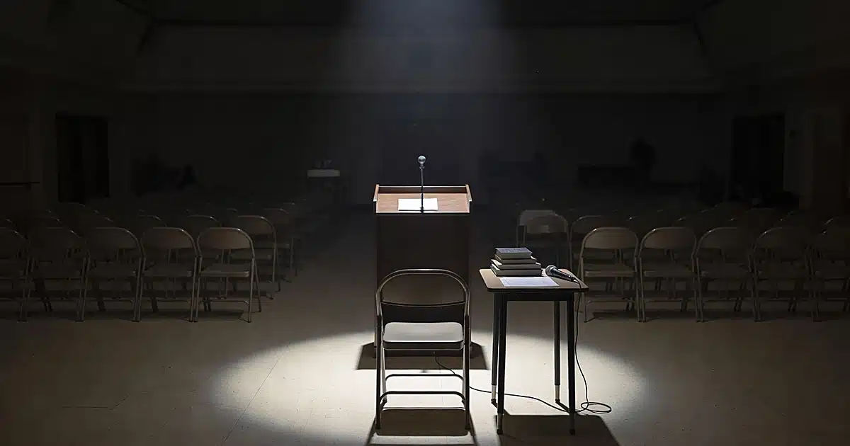 Empty university event space with vacant podium and unused books on table in dim lighting