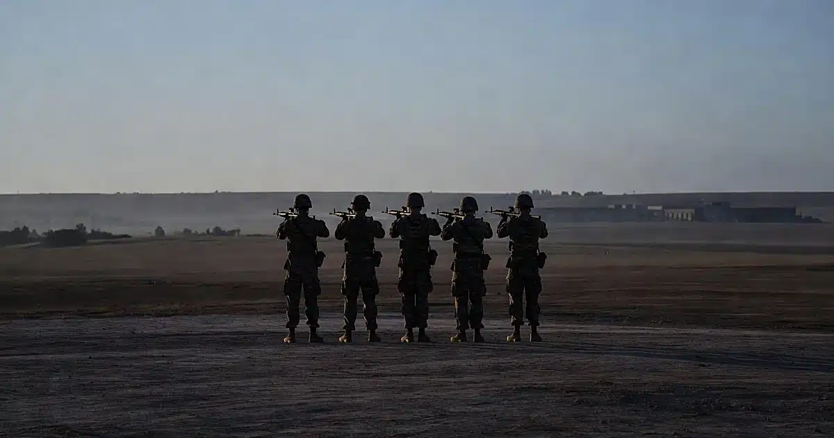 Military firing squad formation silhouetted at dawn on Fort Hood training grounds
