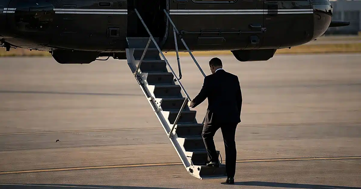 Silhouetted figure descending steep helicopter stairs while gripping railing at military airbase